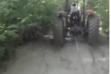 Trator rebocando carro em atoleiro